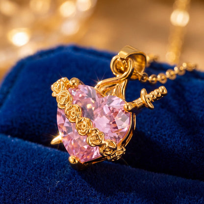 Detalle del dije – guirnalda de rosas doradas y espada sobre el corazón de circón rosado
